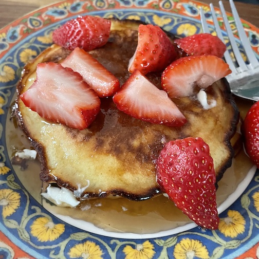 Sourdough Pancakes with maple syrup and cut strawberries